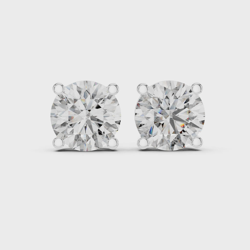 360 degree rotating view of white gold round diamond stud earrings demonstrating diamond fire, basket setting, and refined metal finish