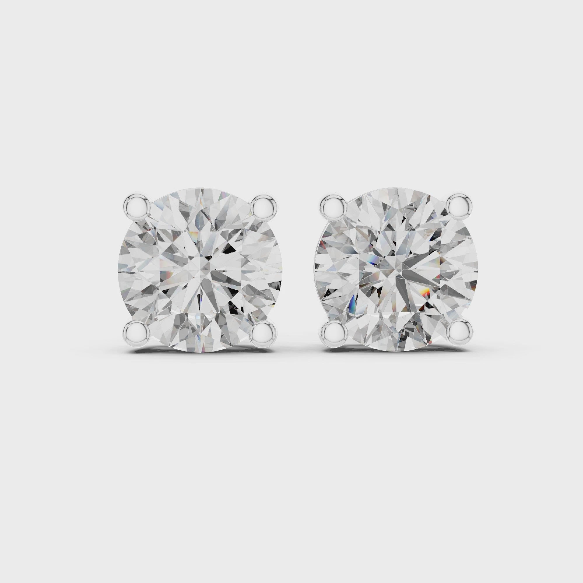 360 degree rotating view of white gold round diamond stud earrings demonstrating diamond fire, basket setting, and refined metal finish